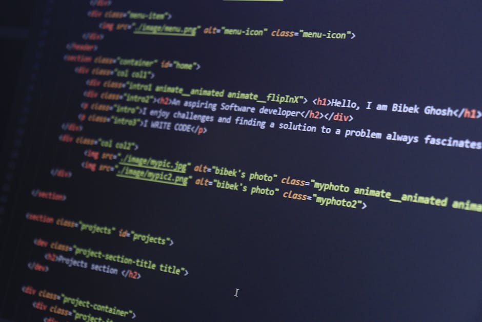 Close-up view of a computer screen displaying lines of HTML code with syntax highlighting in various colors, including red, blue, yellow, and white, on a dark background. The code features tags such a